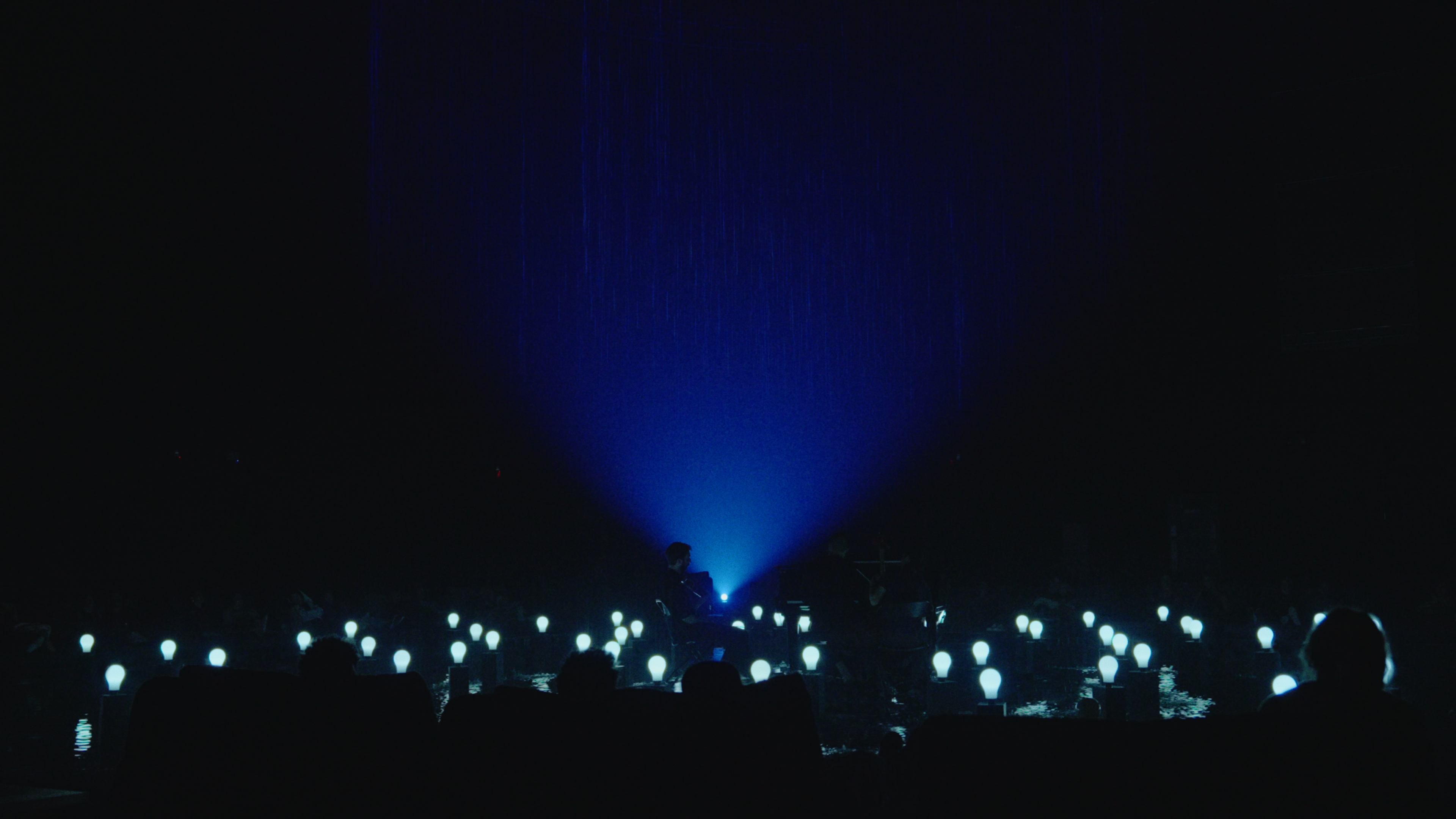 Performance — blue light beam with glowing bulbs on water